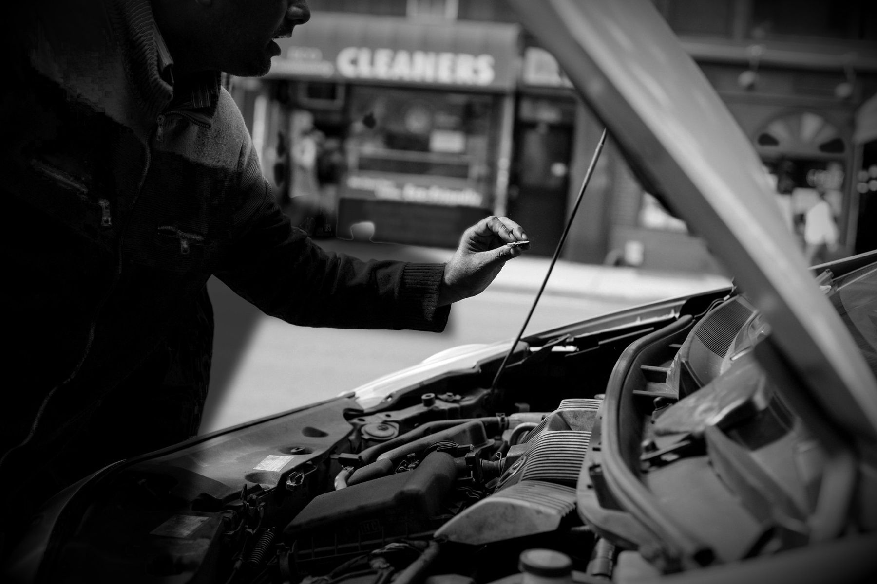 Mechanic in black checking the oil under an open bonnet